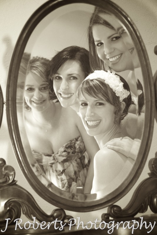 Sepia of bride and bridesmaids looking into an old fashioned mirror - wedding photography sydney